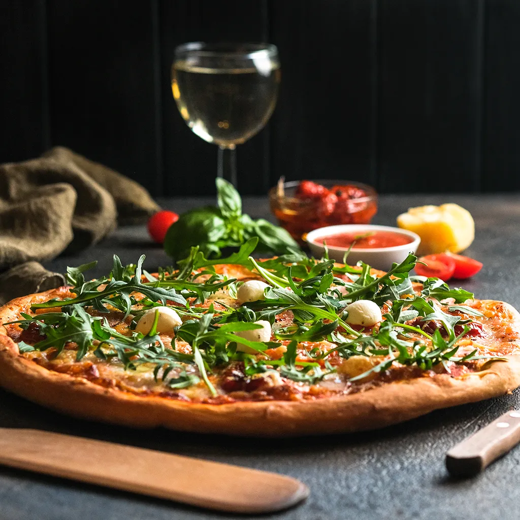Pizza mit einem Glas Wein im Hintergrund